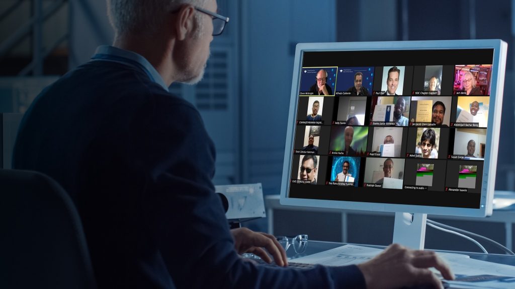 a man sitting in front of a computer screen with many people on it.