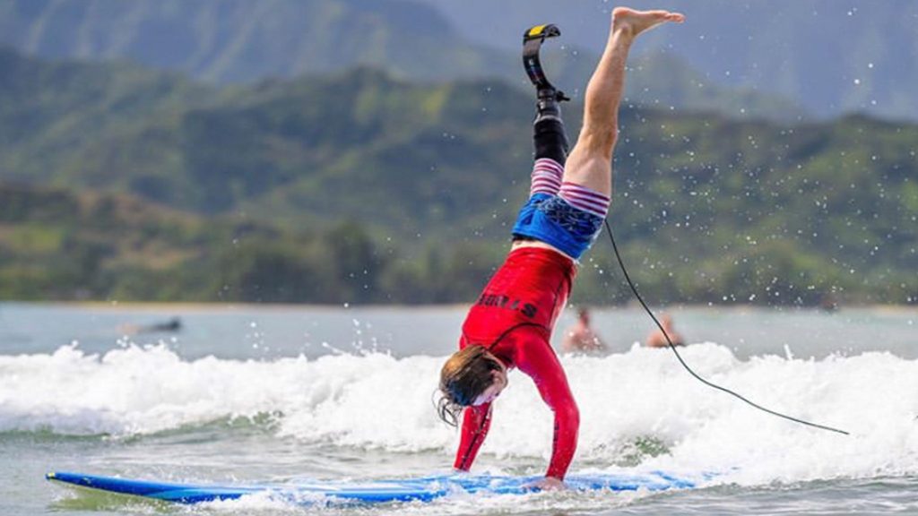 a person doing a handstand on a surfboard.