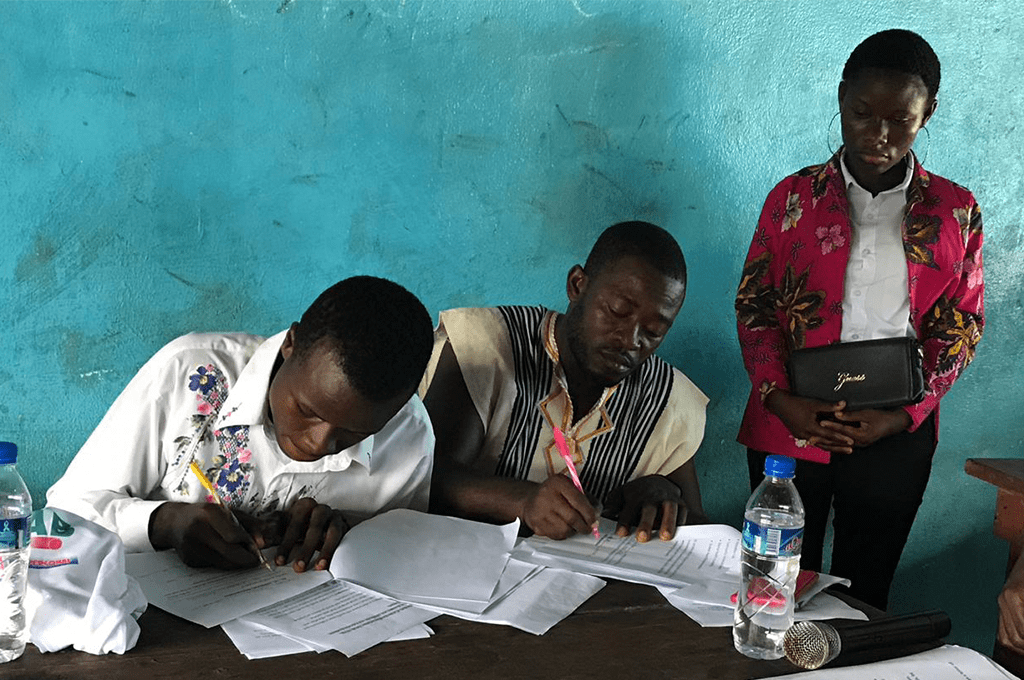 a group of people signing papers at a table.