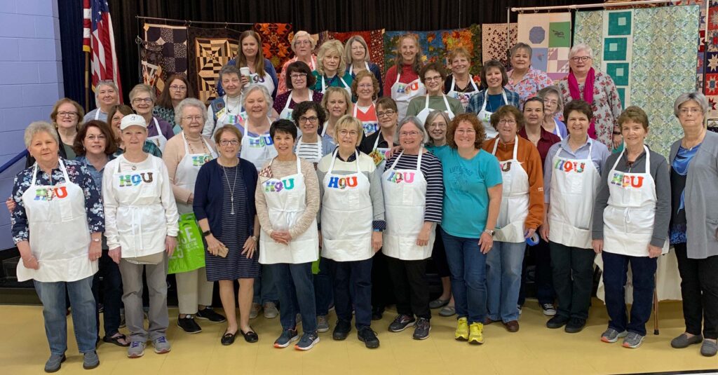 a group of women in aprons posing for a photo.