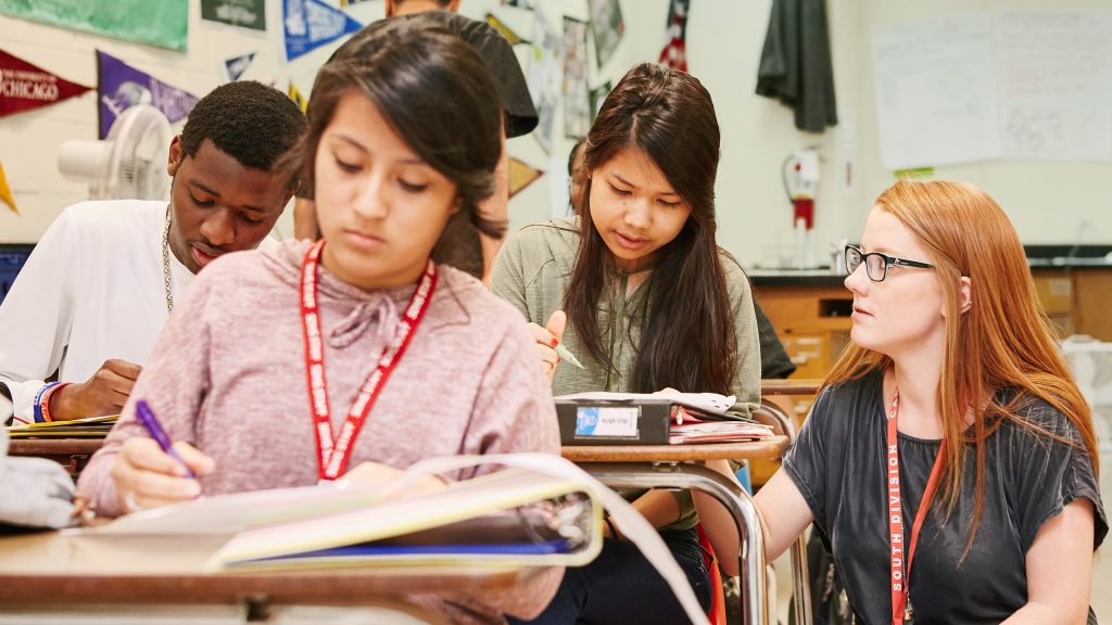 a group of students sitting at desks in a classroom.