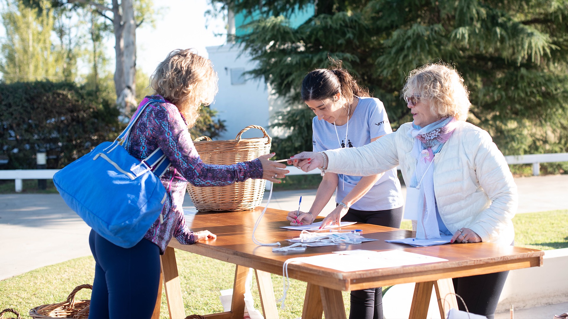 two women shaking hands at a table in a park.