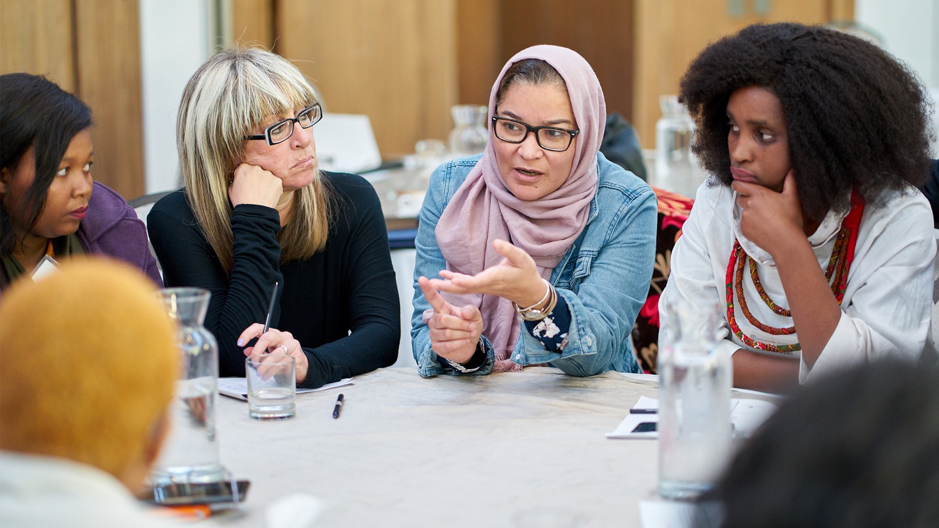 a group of women sitting around a table talking.