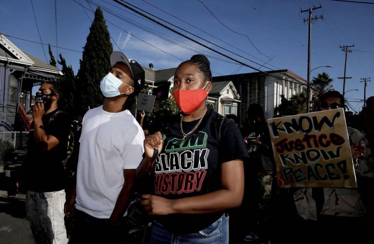 a group of people wearing masks and holding signs.