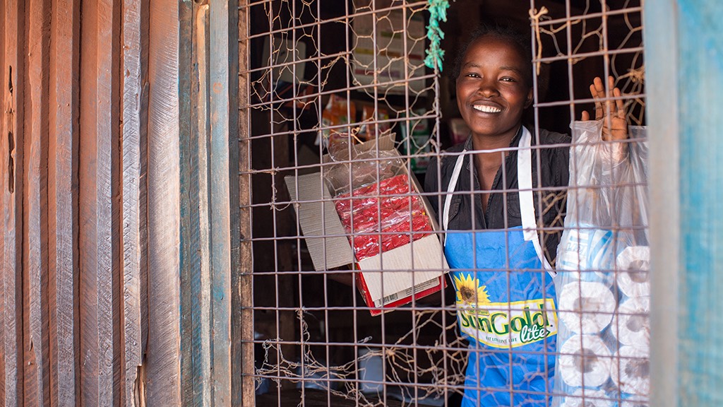 a woman smiles through the window of a shop.