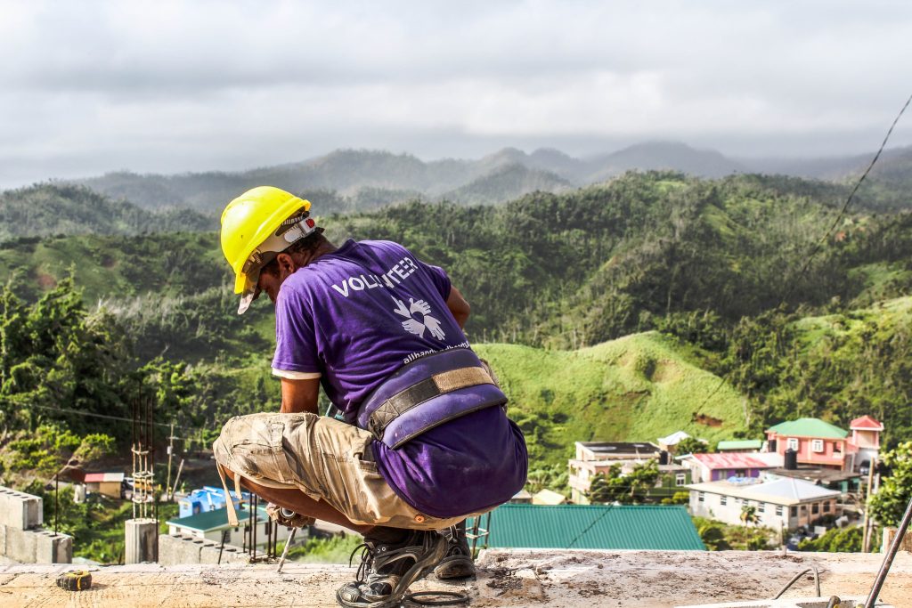 a man in a purple shirt is kneeling on top of a hill.