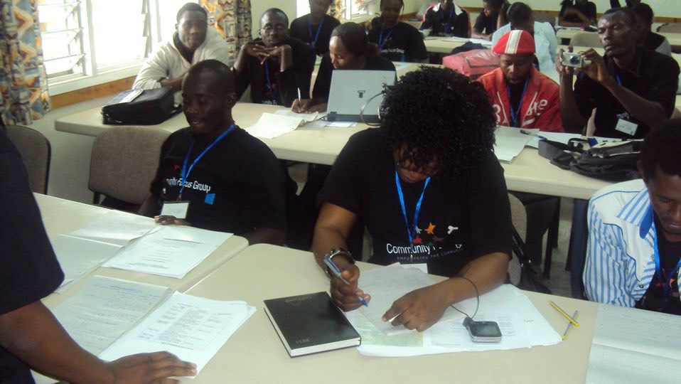 a group of people sitting at a table in a classroom.