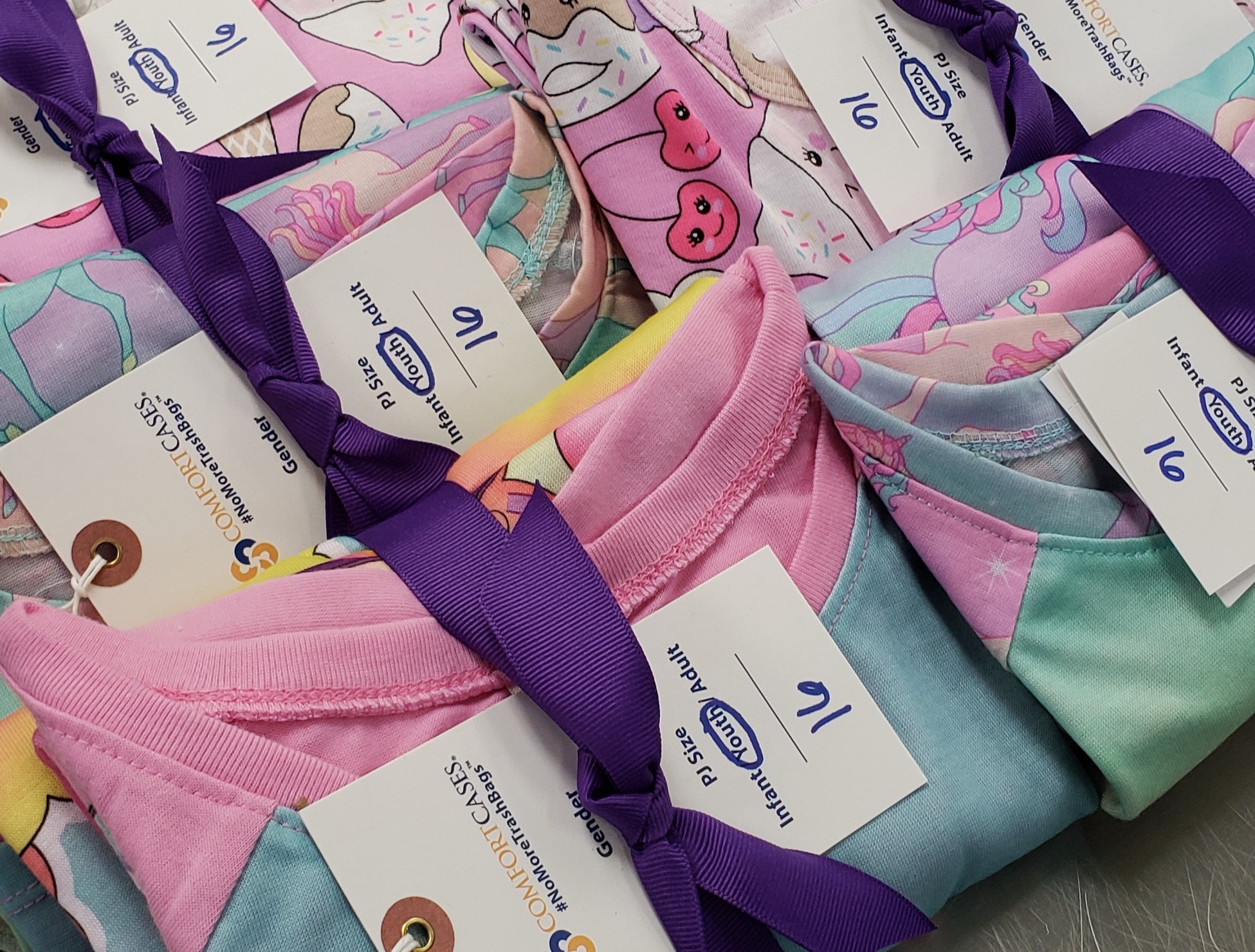 a stack of pink and purple t - shirts on a table.