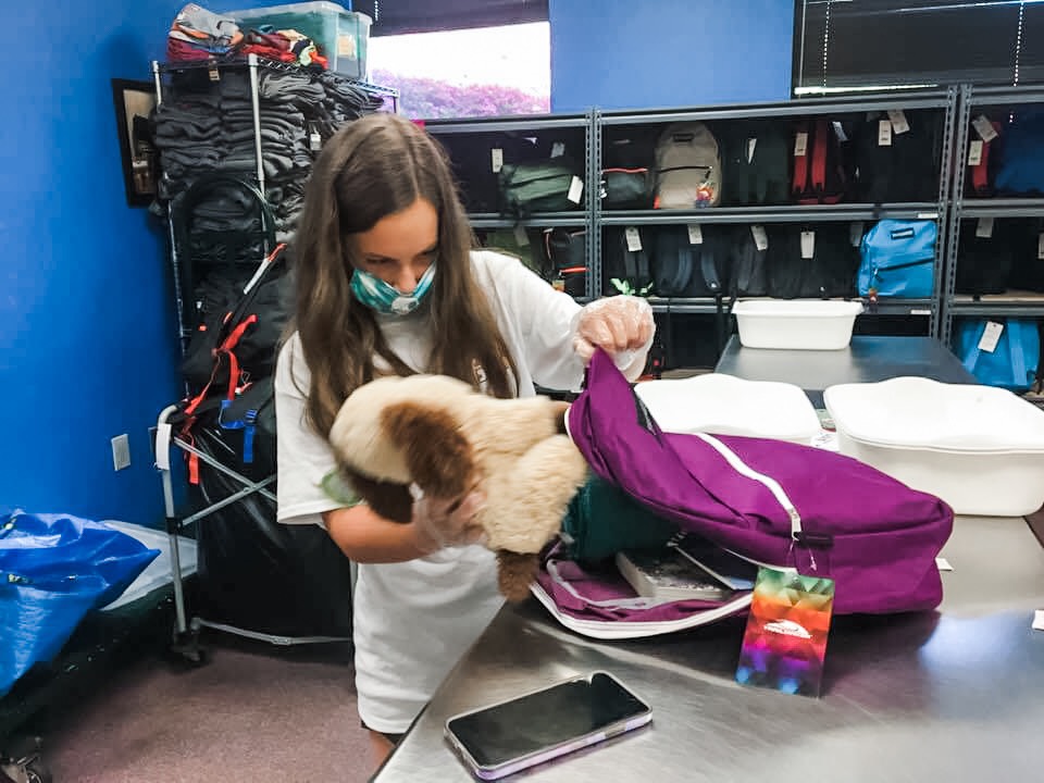 a girl wearing a mask and carrying a stuffed animal.