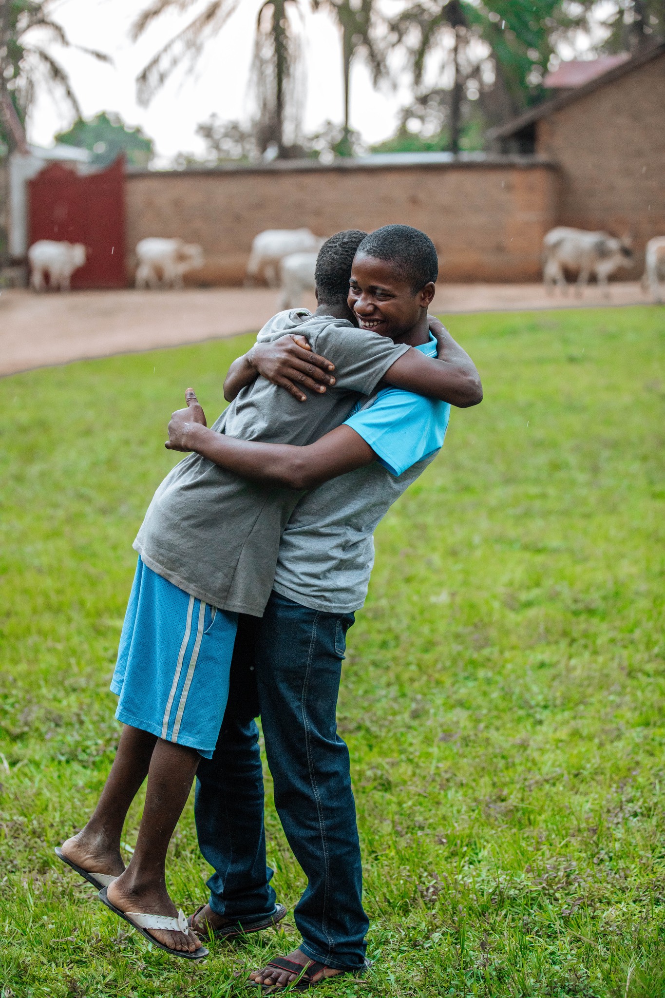 two boys hugging each other in a field.