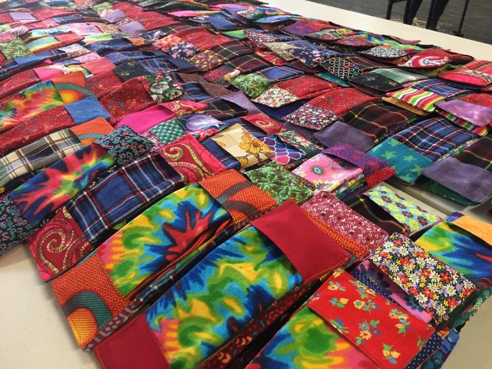 a table full of colorful quilts on a table.