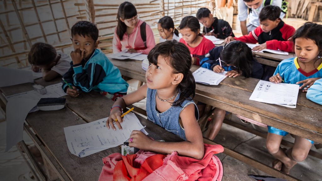 a group of children sitting at desks in a classroom.