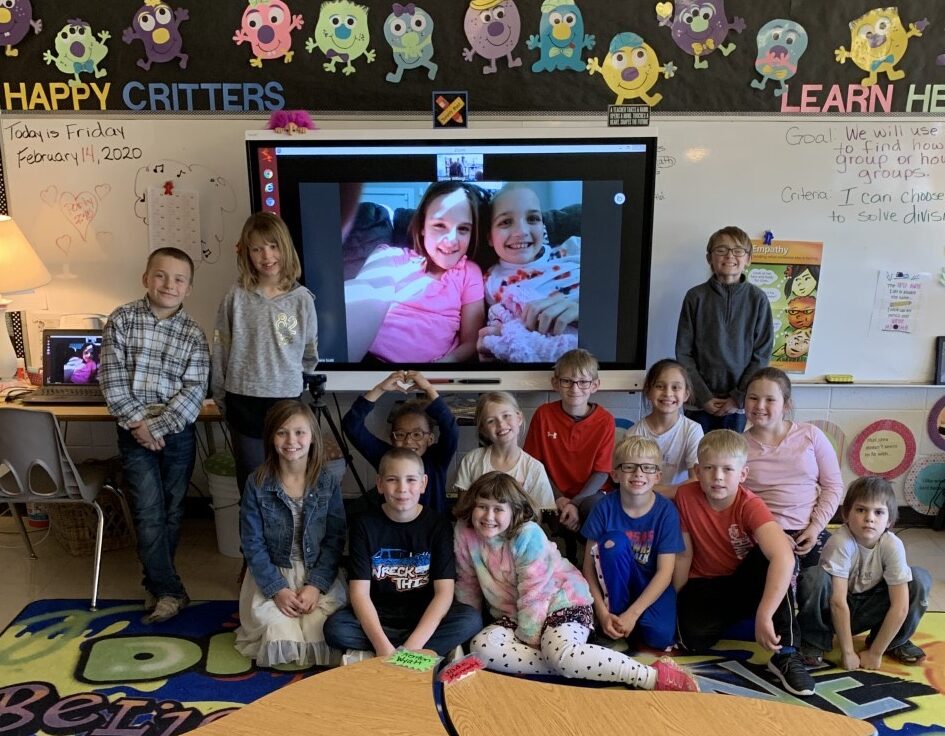 a group of children posing in front of a tv screen.