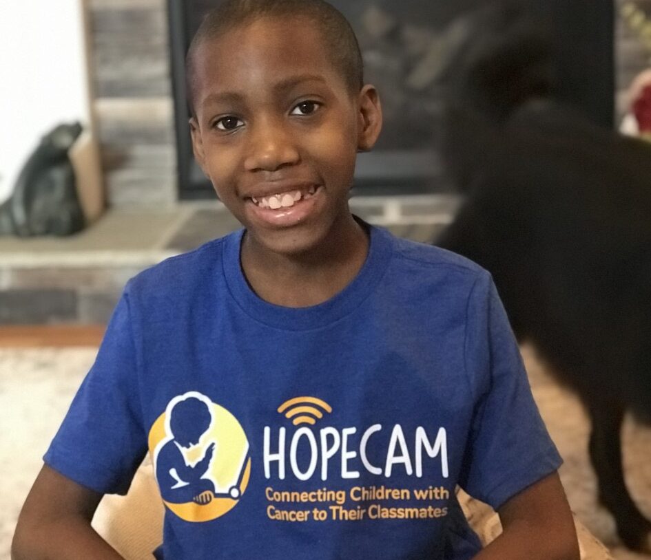 a young boy in a blue t - shirt smiles at the camera.