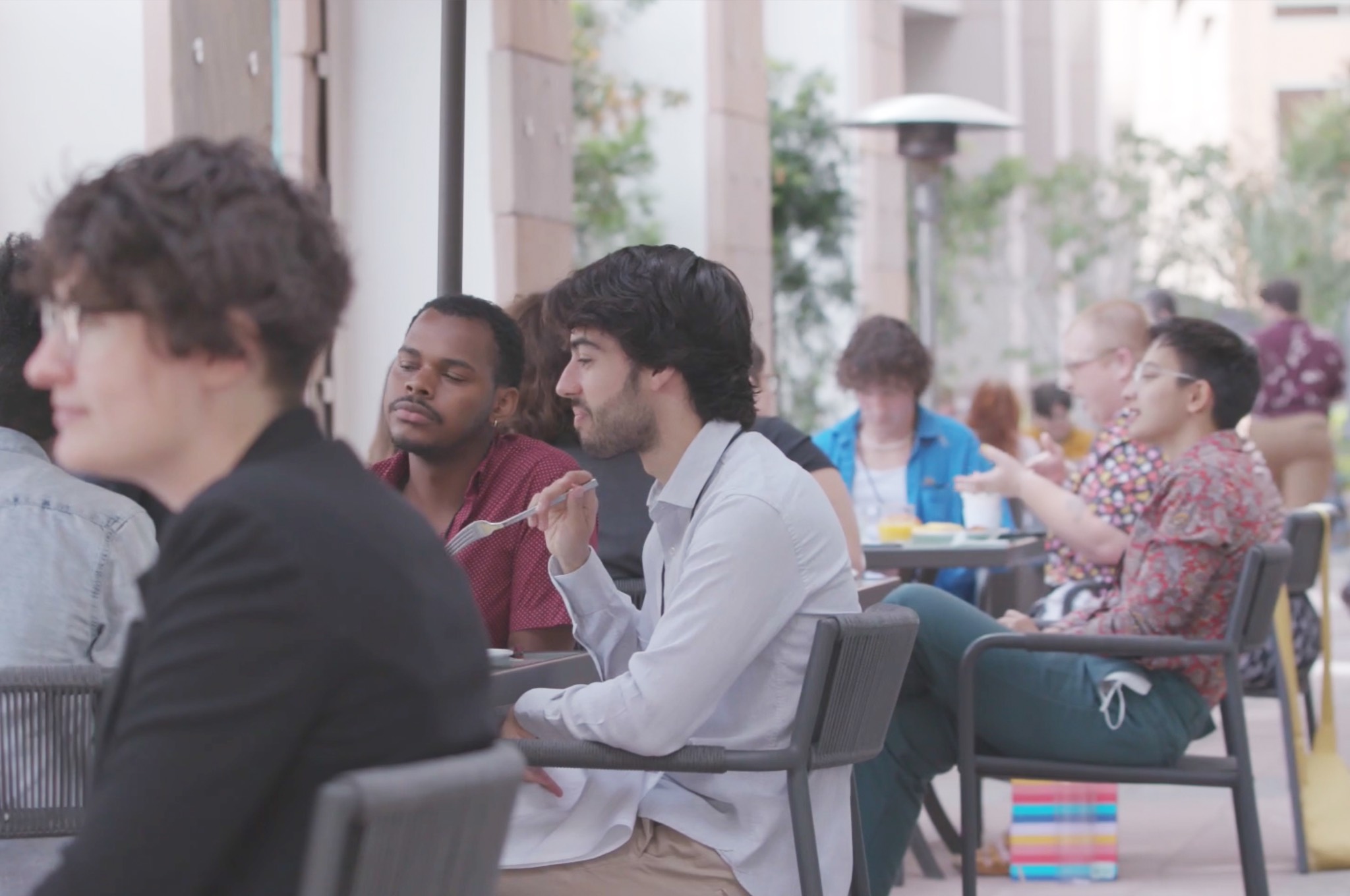 a group of people sitting at tables in an outdoor area.