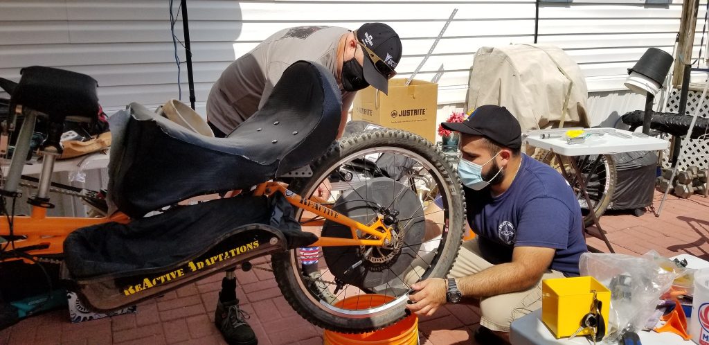 two men working on a bicycle in a backyard.