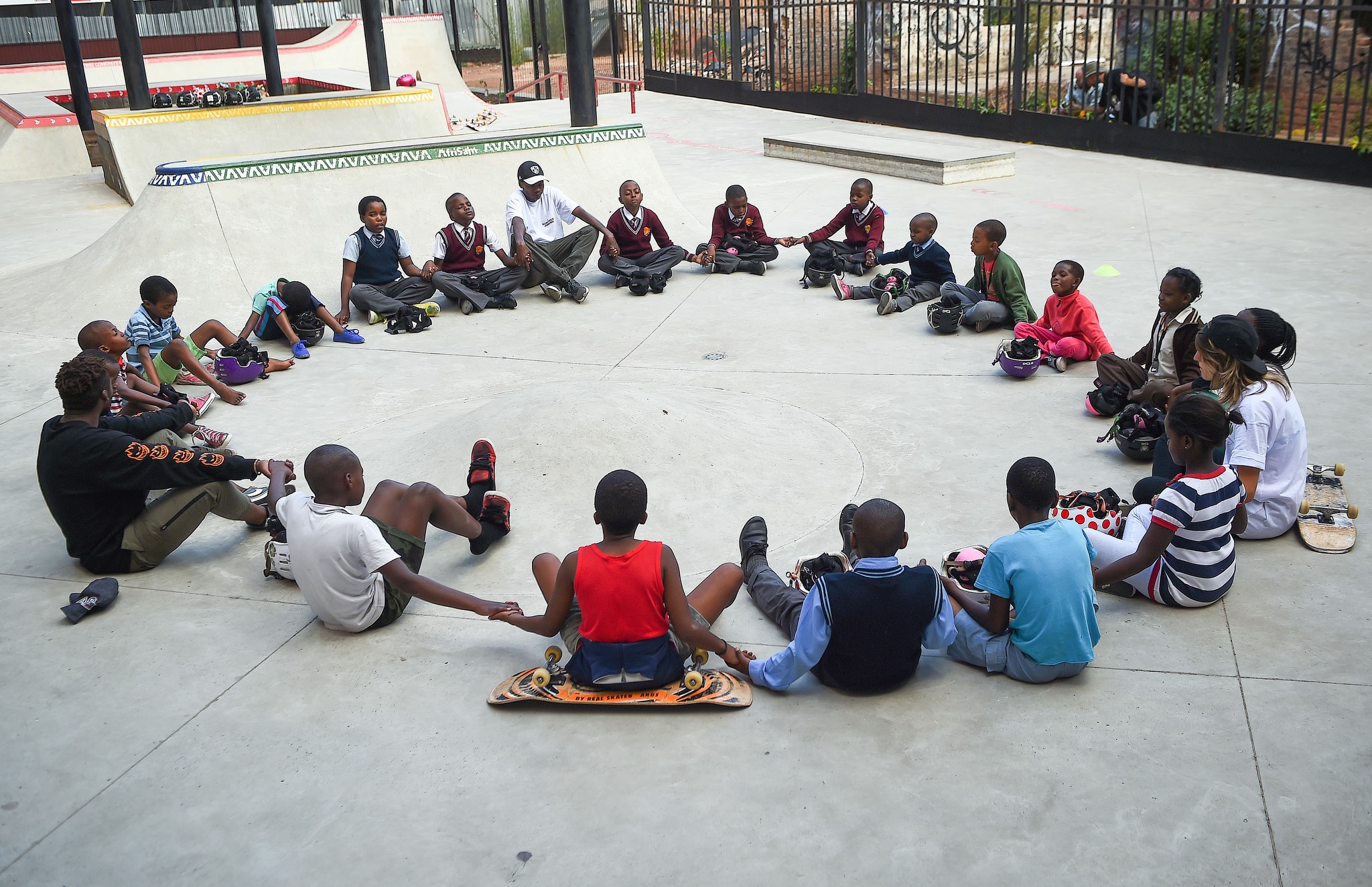 a group of children sitting in a circle on a skateboard.