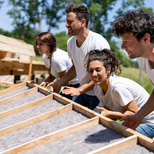 Group of people engaged in outdoor teamwork activity, possibly a community service or building project.